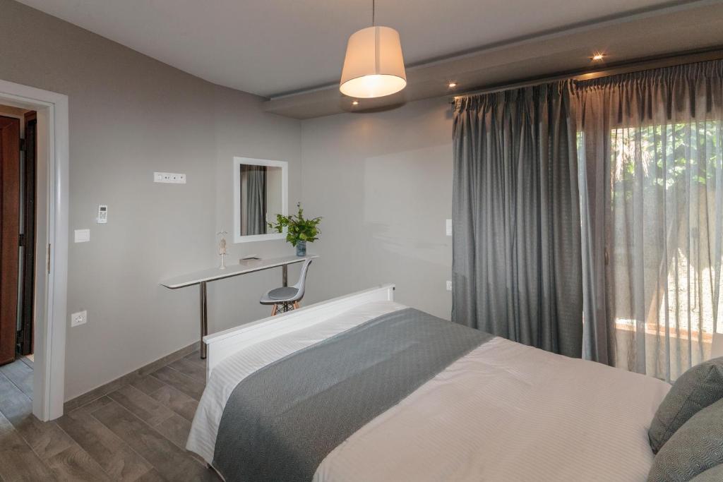 a bedroom with a bed and a desk and a window at Kissos Apartments in Vourvourou