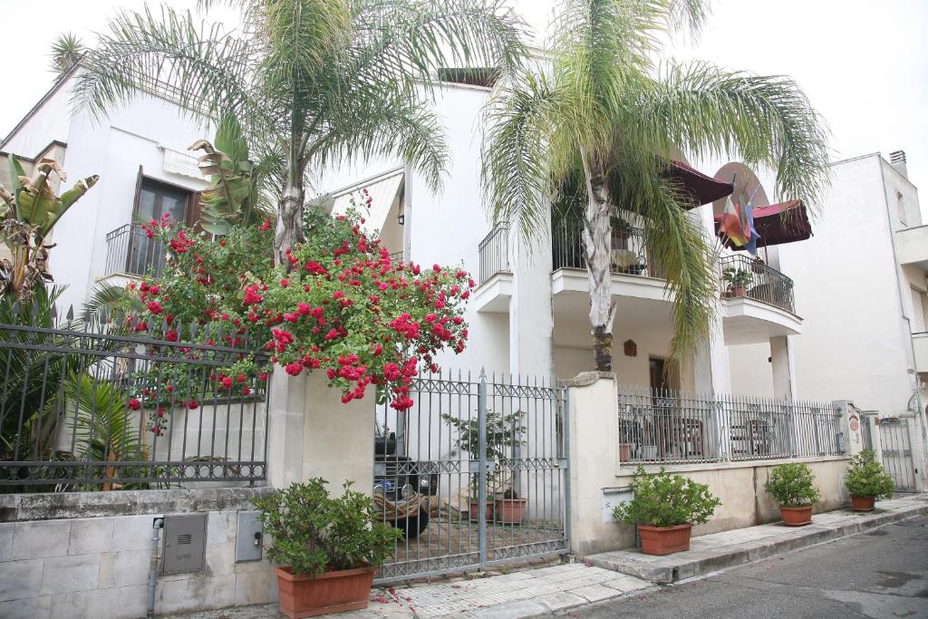 a white building with palm trees and pink flowers at Residence Angelica in Oria