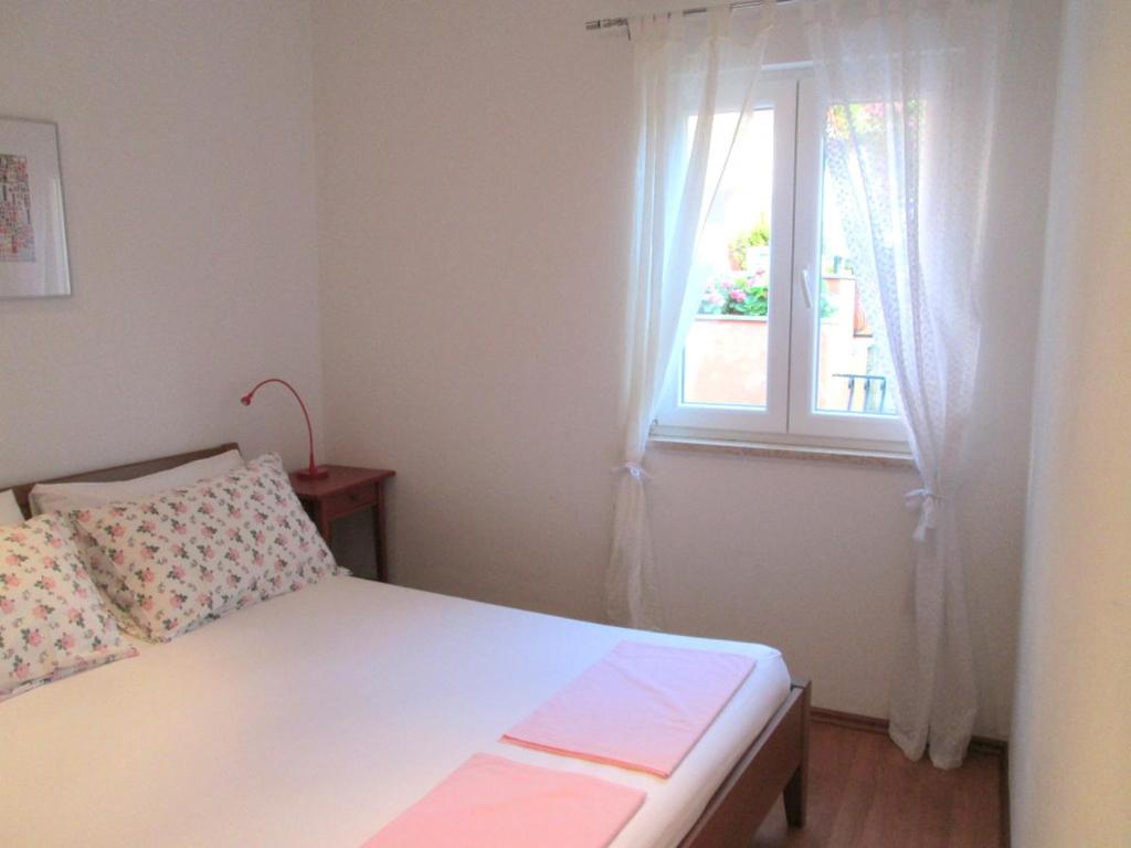 mała sypialnia z łóżkiem i oknem w obiekcie Apartment San Elena w Rovinj