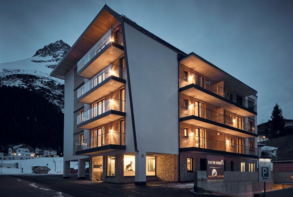 a building with lights on in front of a mountain at Silva Peak Residences Galtür - incl Sommer Premium Silvretta Card in Galtür