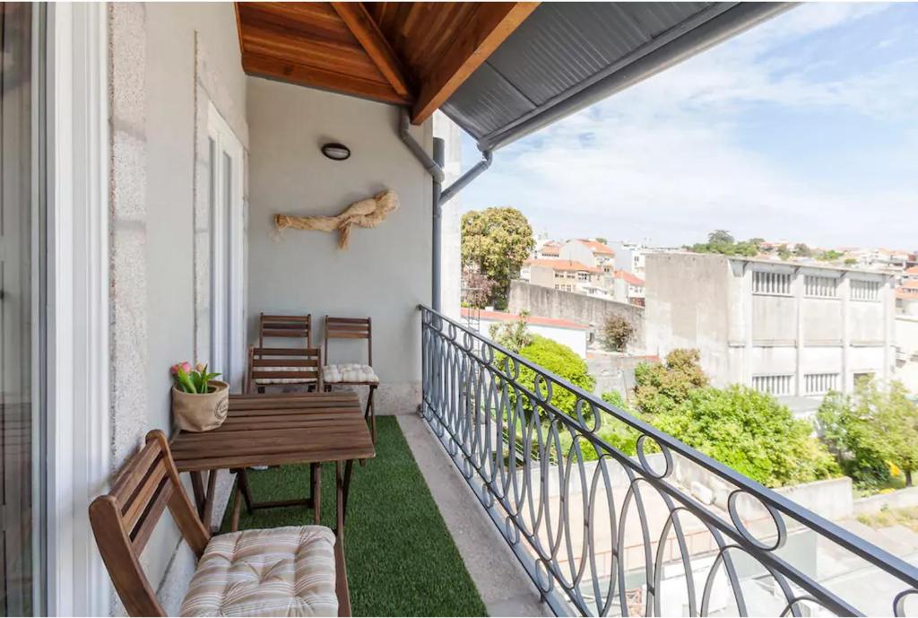 einen Balkon mit einem Holztisch und Stühlen darauf in der Unterkunft Boutique Rentals - Boho Chic Apartment in Porto