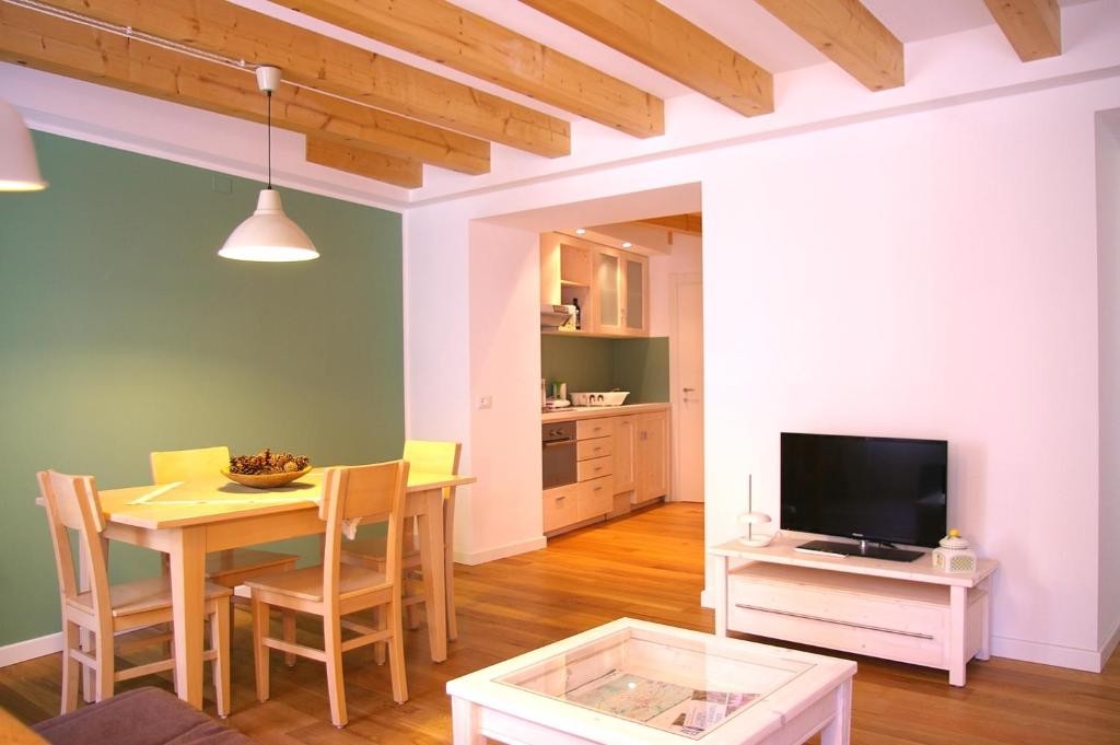 cocina y comedor con mesa y TV en Trentino Apartments - Il Gufo Vacanze, en Borgo
