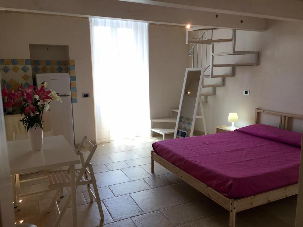 a bedroom with a purple bed and a staircase at Cantaluna B&B in Polignano a Mare