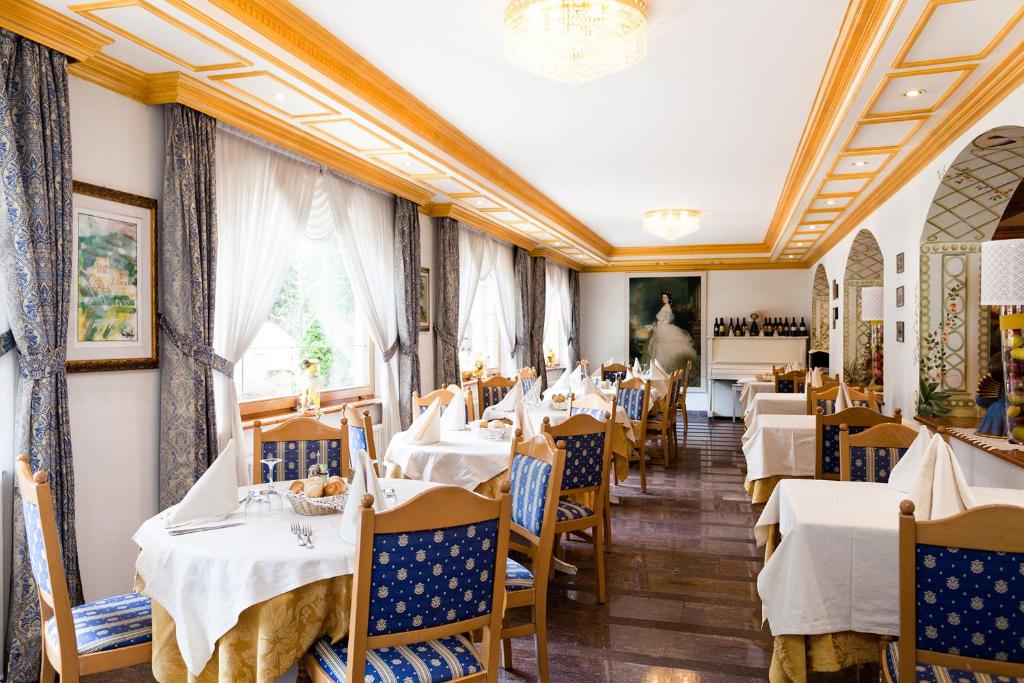 a restaurant with white tables and blue chairs at Hotel Vienna in San Martino di Castrozza