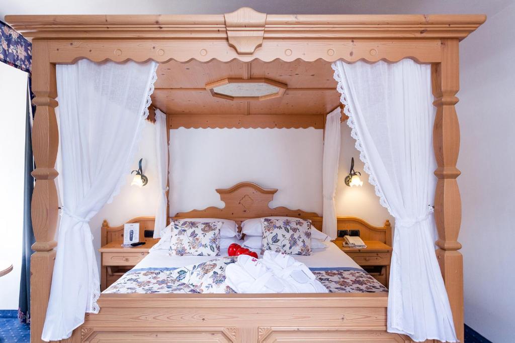 a bedroom with a canopy bed with white curtains at Hotel Vienna in San Martino di Castrozza