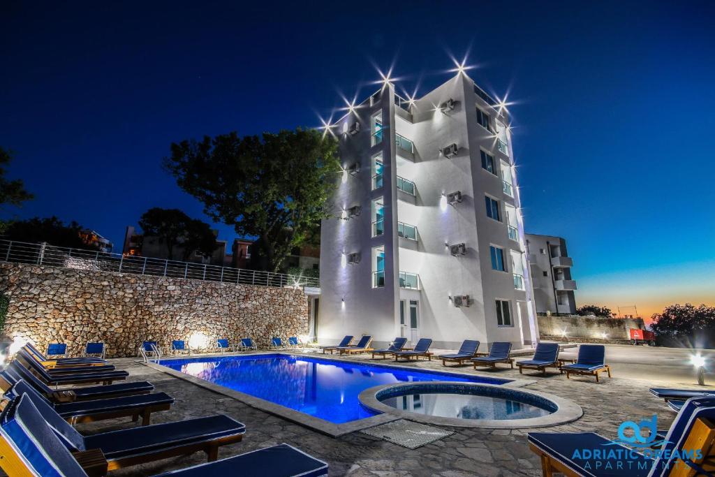 un hotel con piscina frente a un edificio en Adriatic Dreams Apartments, en Dobra Voda