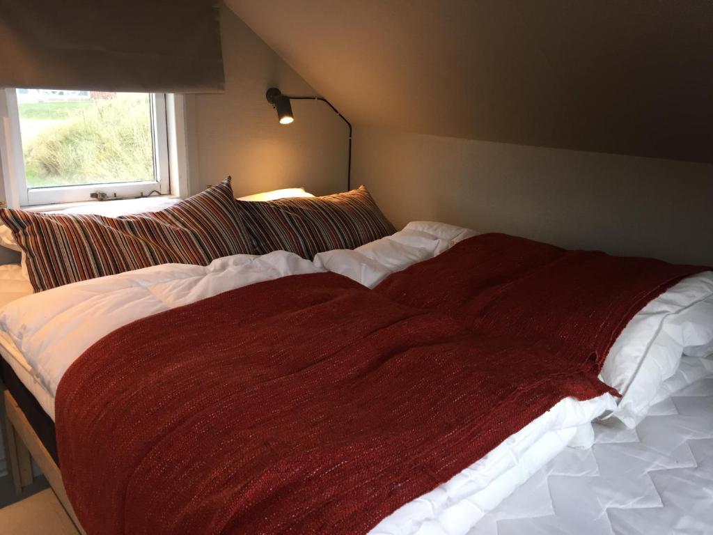 uma cama com um cobertor vermelho num quarto em Dancamps Nordsø Water Park em Hvide Sande