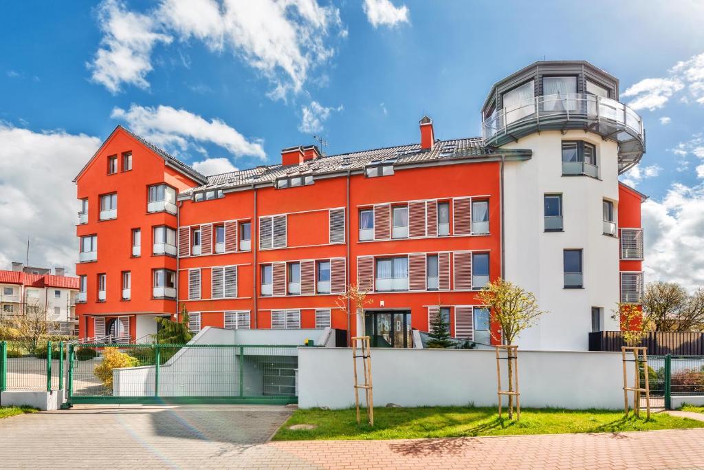 an orange and white building with a balcony at Apartamenty Sun & Snow Latarnia in Władysławowo
