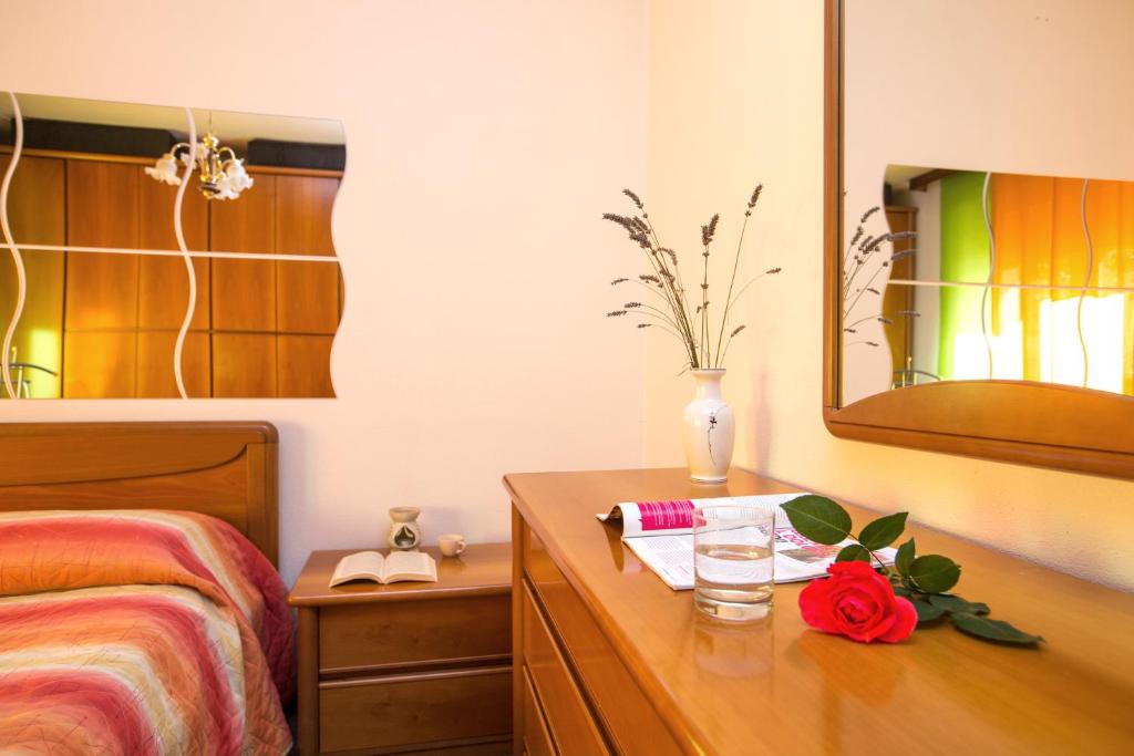 ein Schlafzimmer mit einem Bett und einer Kommode mit einer Blume darauf in der Unterkunft Free Hugs in Mazzo di Valtellina