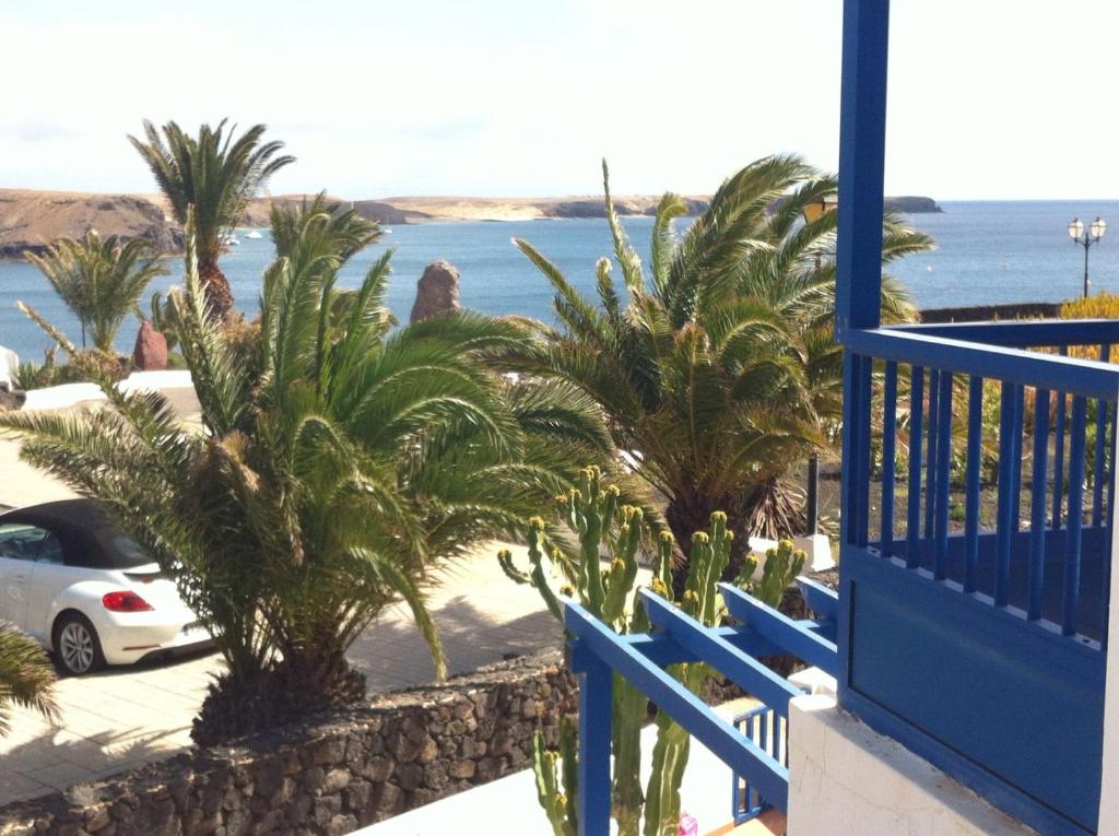 un balcón azul con palmeras y el océano en Las Moreras Apartment 135, en Playa Blanca