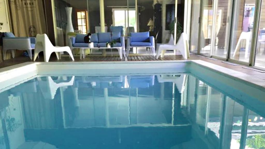una piscina con sedie bianche e sedie blu di Les Rêveries a Chazé-sur-Argos