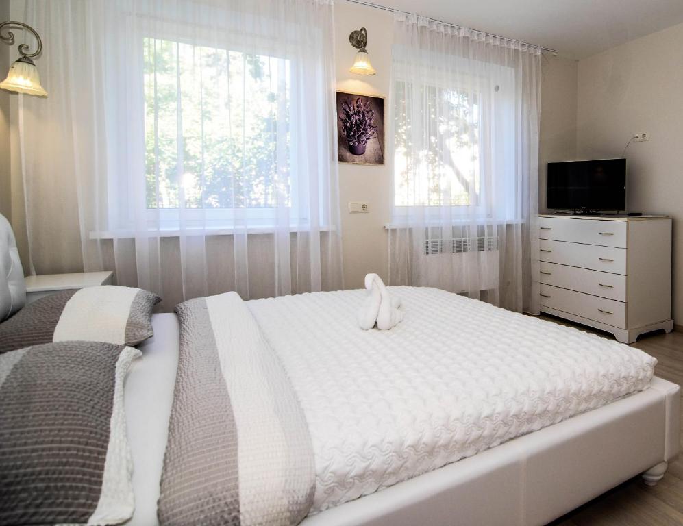 Un dormitorio con una cama blanca con un animal de peluche. en Elena, en Palanga