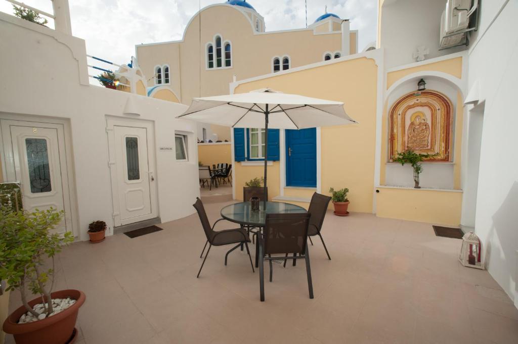 eine Terrasse mit einem Tisch, Stühlen und einem Sonnenschirm in der Unterkunft Lefteris Traditional Rooms in Fira