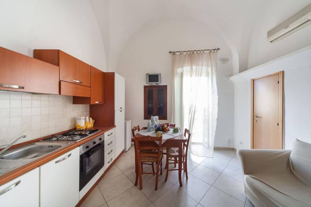 una cucina con tavolo e sedie e una cucina con piano cottura di Monolocale finemente ristrutturato a Ostuni