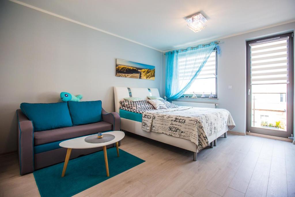 - une chambre avec un lit, un canapé et une table dans l'établissement Apartament Kompas, à Świnoujście