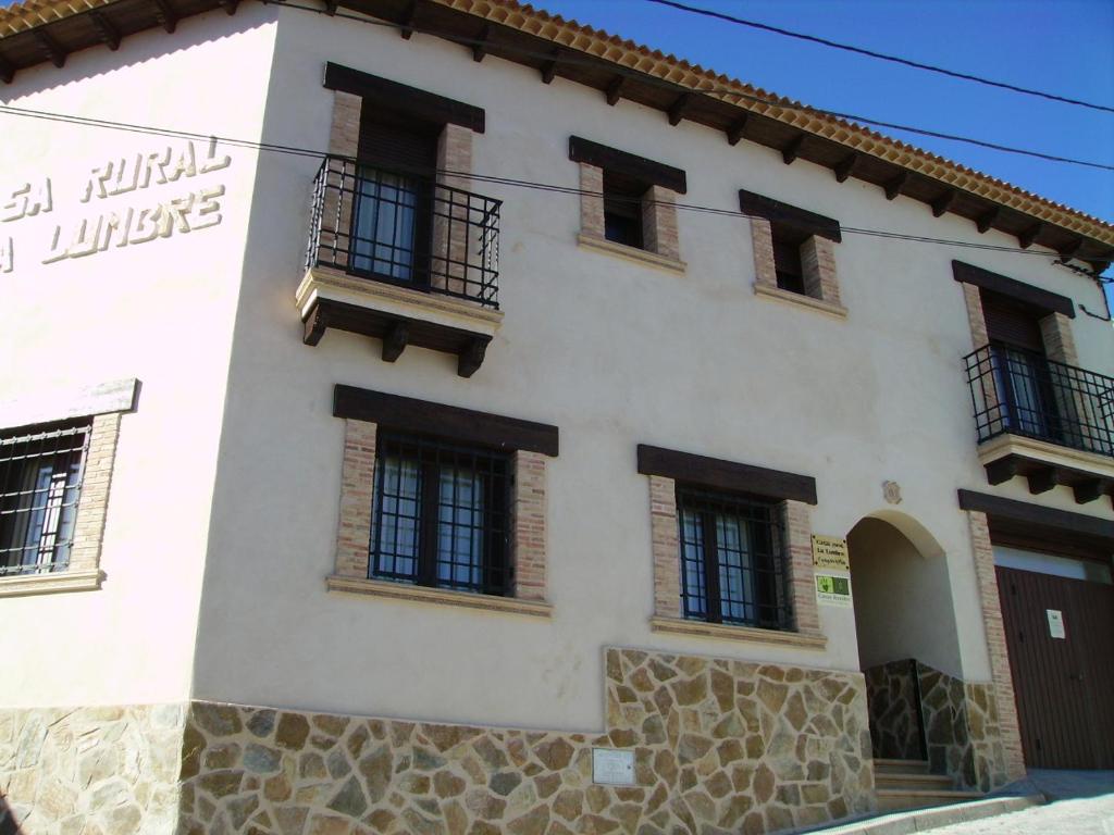 a white building with windows and a balcony at Casa Rural La Lumbre in Enguídanos