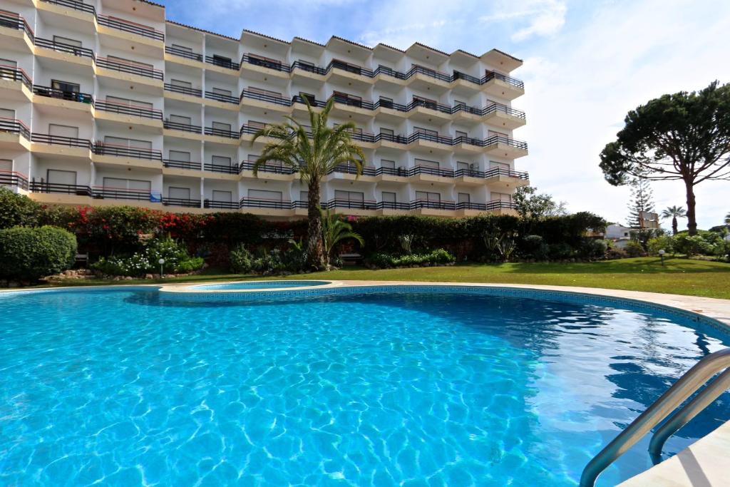 a swimming pool in front of a building at Marbel Sol - Clever Details in Vilamoura