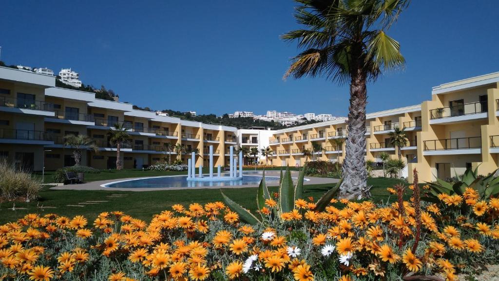 um grande edifício com uma palmeira e flores em Apartamento luxo e sossego em Albufeira