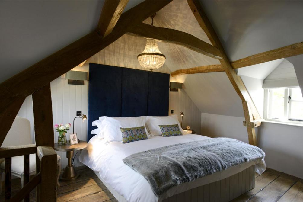 a bedroom with a large bed with a blue headboard at Walnut Cottage in Moreton in Marsh