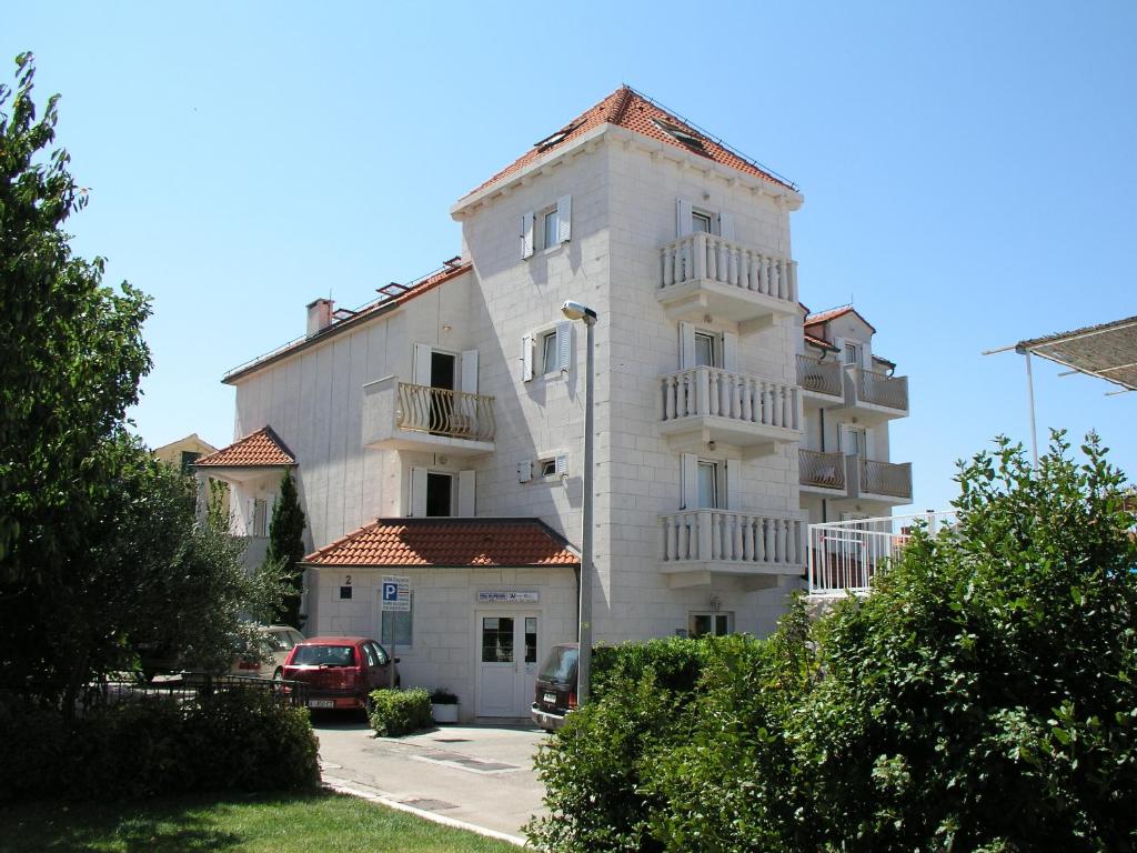 un gran edificio blanco con un coche aparcado delante de él en Villa Supetar, en Supetar