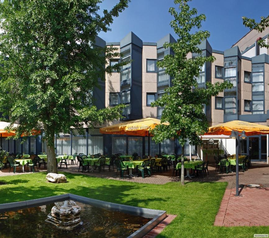 a courtyard with a pond and tables and a building at H+ Hotel Köln Brühl in Brühl