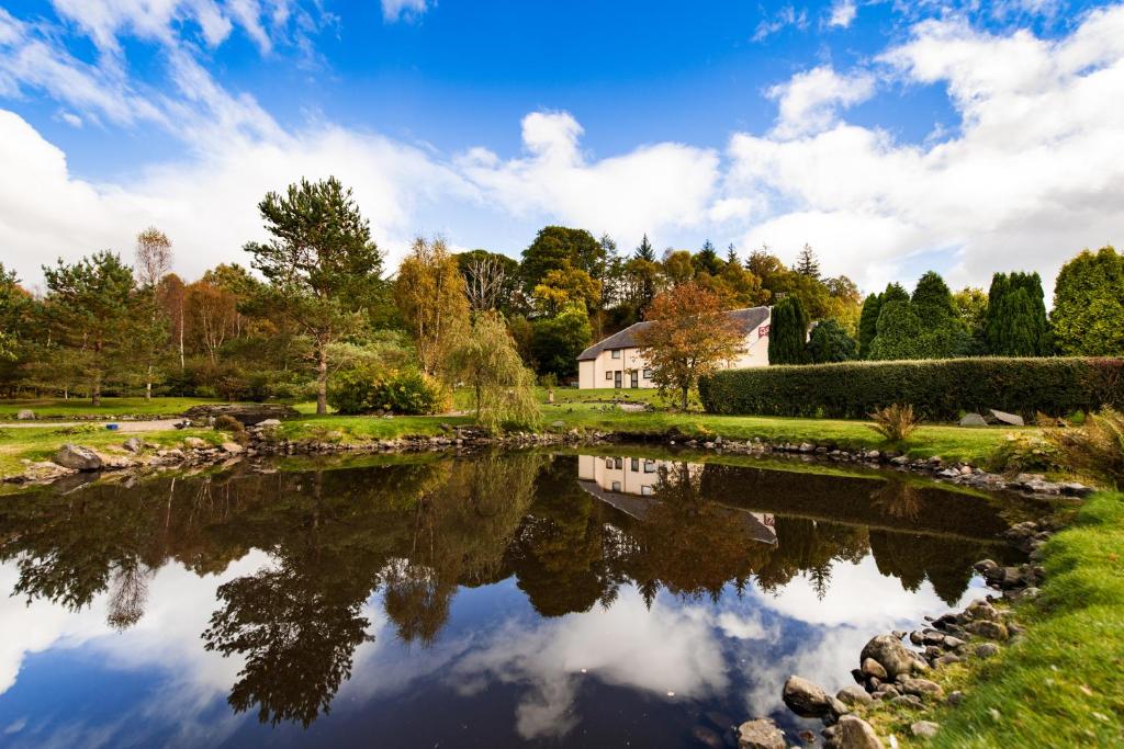 una casa reflejada en el agua de un lago en The Stronlossit Inn en Fort William