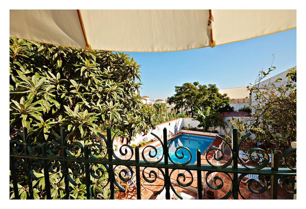 a black iron fence with a swimming pool behind it at Hostal La Posada in Conil de la Frontera