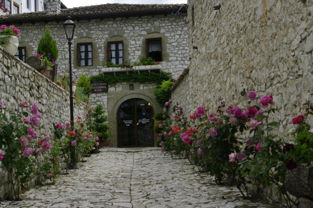 an alley with flowers in front of a stone building at Hotel Klea in Berat