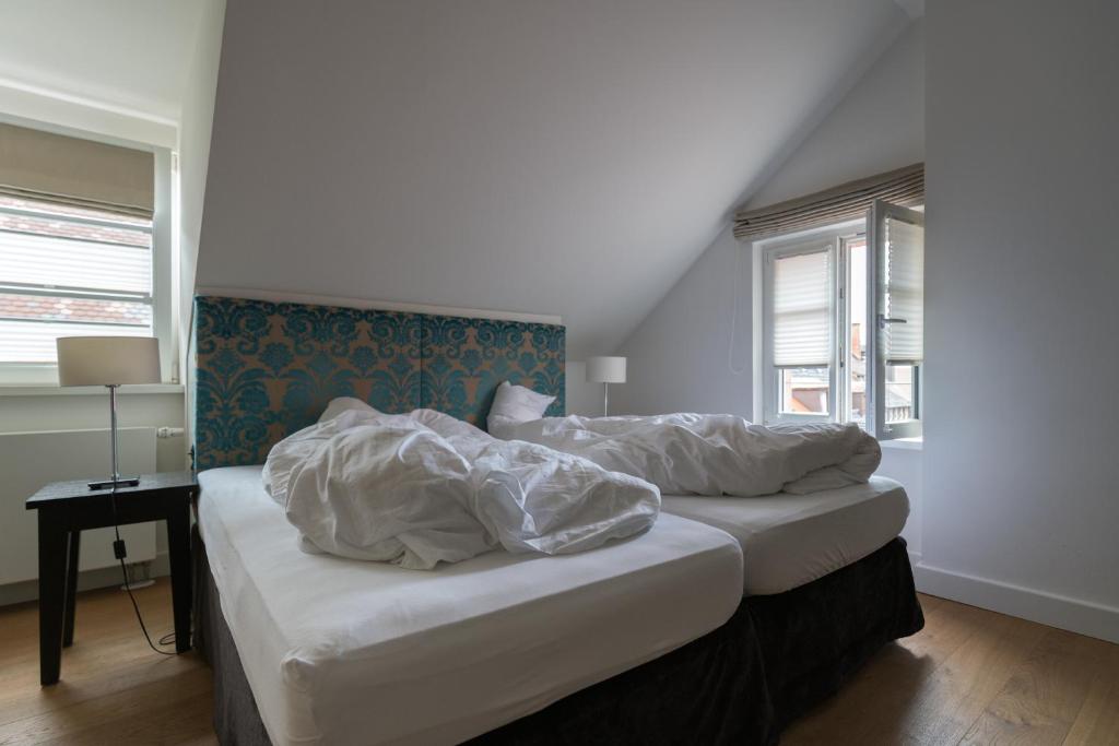 フライブルク・イム・ブライスガウにあるホテル シュヴァルツヴェルダー ホフのベッドルーム1室(白いシーツが備わるベッド2台付)