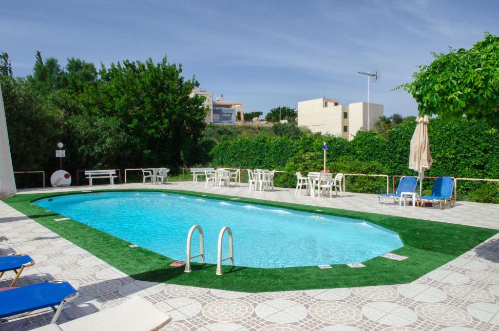 a swimming pool with chairs and a table and chairs at Alkion Hotel in Stalos