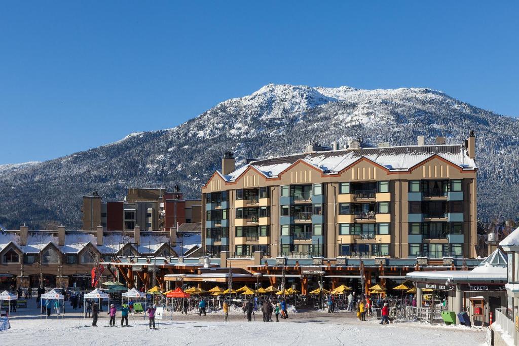 a large building with a mountain in the background at Gibbons Life Accommodations in Whistler