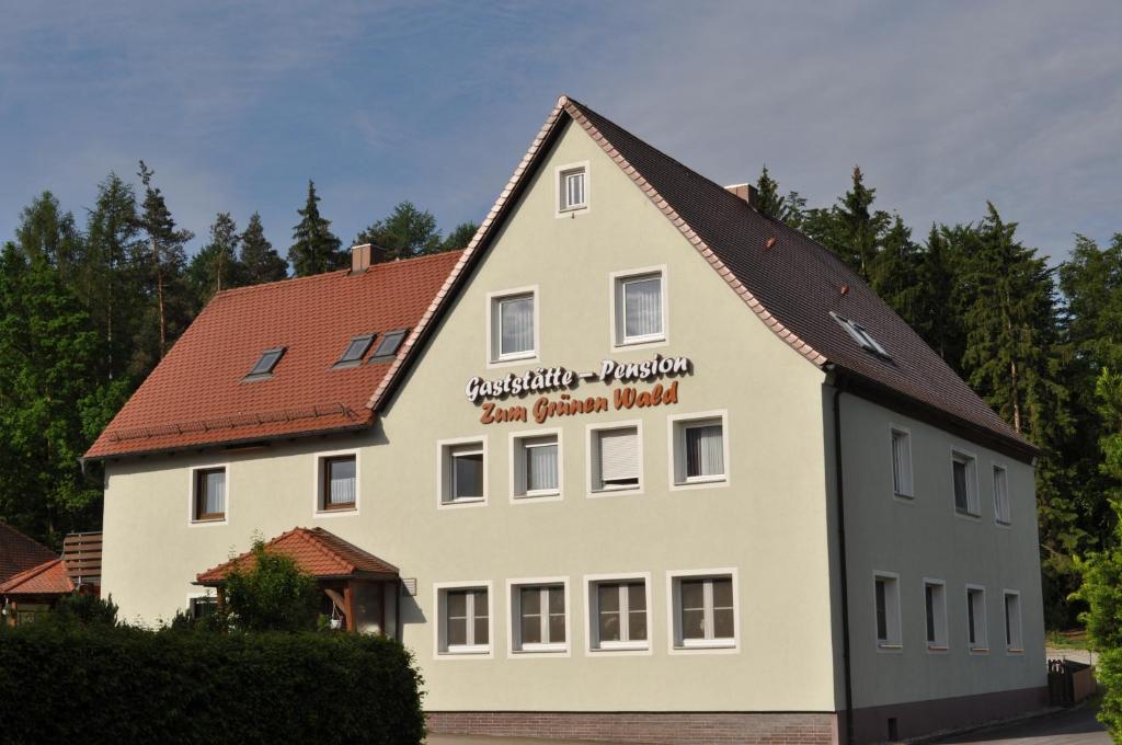 ein großes weißes Gebäude mit einem Schild drauf in der Unterkunft Pension Zum Grünen Wald in Feuchtwangen