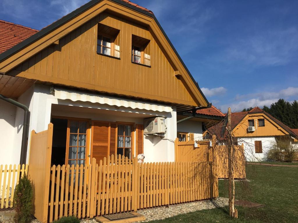 une maison avec une clôture en bois devant dans l'établissement Apartma Jelenček, à Moravske Toplice