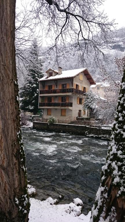 a building next to a river in the snow at La Capelette in Ax-les-Thermes