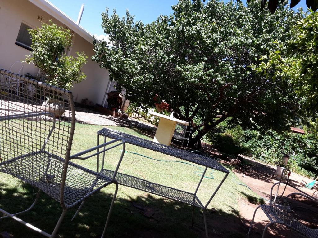 a bird cage sitting in the grass near a house at Heila's in house Family room-Homestay! in Bloemfontein