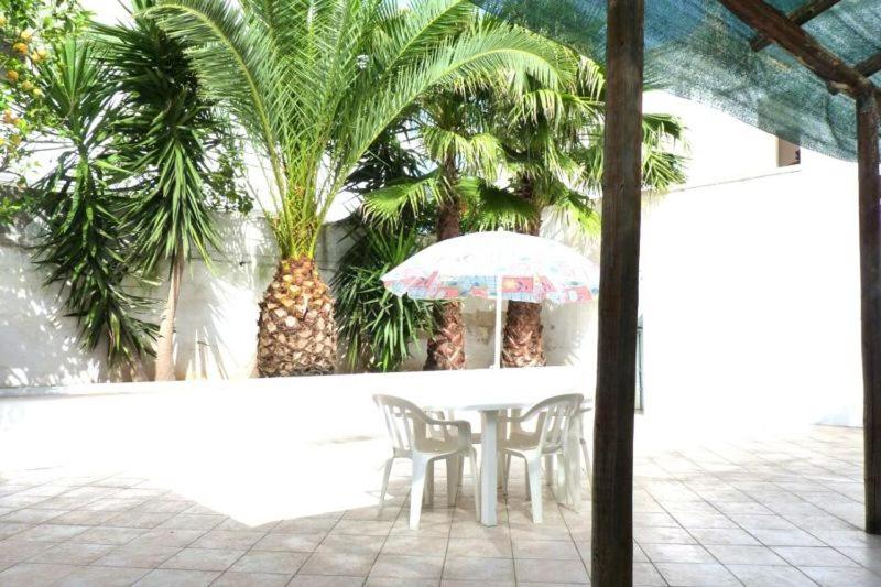 リド・マリーニにあるCasa Annaritaの傘とヤシの木が並ぶテーブルと椅子