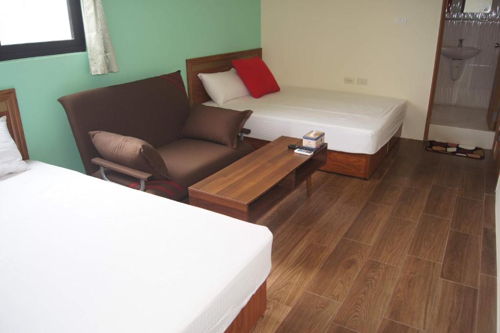 a room with two beds and a couch and a chair at Shimmer B&B in Magong