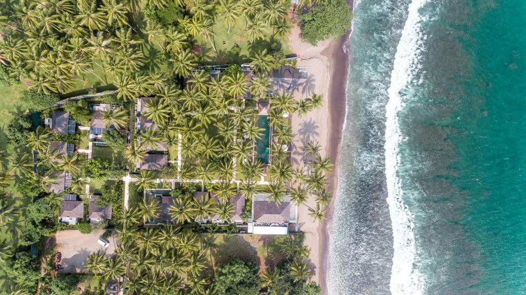 an aerial view of a resort with palm trees and the ocean at The Chandi Boutique Resort & Spa in Senggigi
