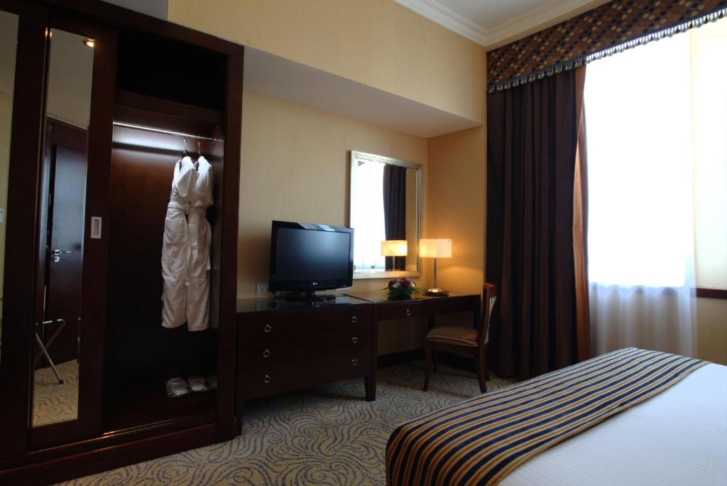 a hotel room with a bed and a dresser and a television at Concorde Hotel Fujairah in Fujairah