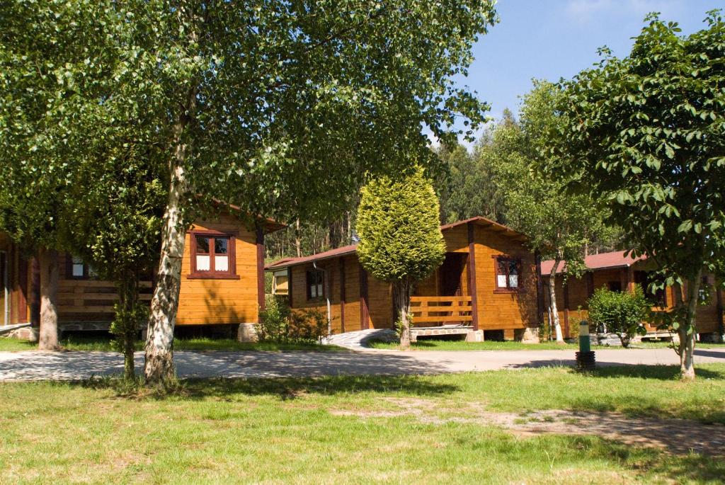 Camping Villaviciosa في La Rasa Selorio: كابينة خشب أمامها أشجار
