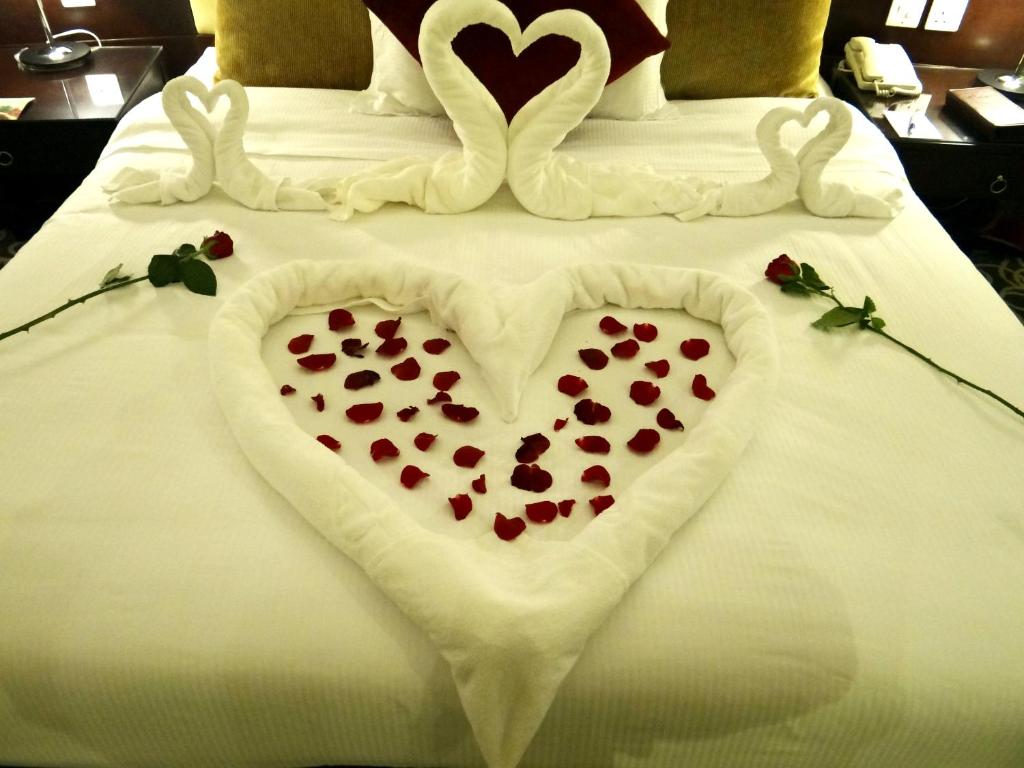a bed with two swans making a heart on it at Concorde Hotel Fujairah in Fujairah