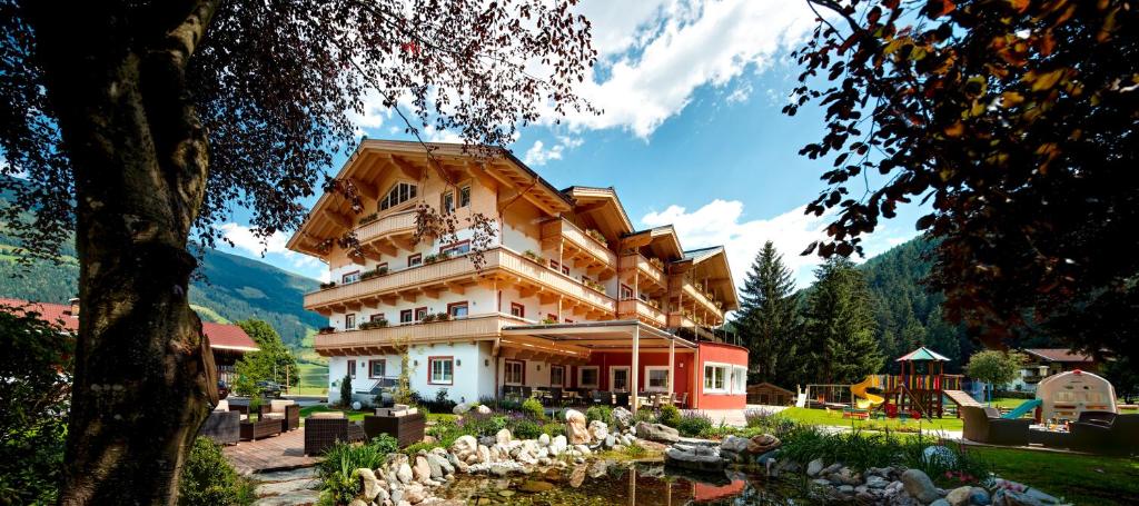 ein großes Gebäude mit einem Teich davor in der Unterkunft Hotel Grundlhof in Bramberg am Wildkogel