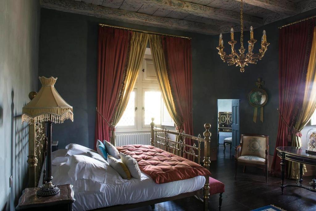 a bedroom with a bed with red curtains and a chandelier at Chateau de Canac in Rodez