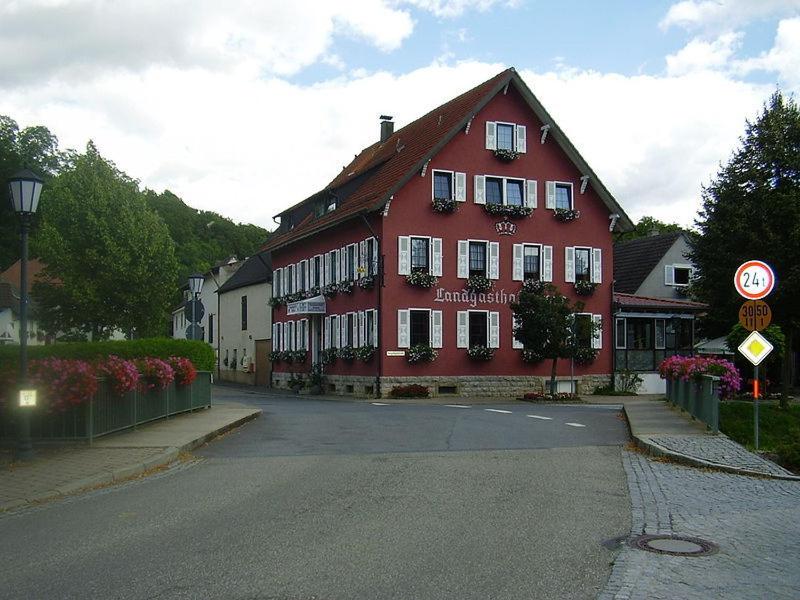 un grand bâtiment rouge sur le côté d'une rue dans l'établissement Landgasthof Krone, à Möckmühl