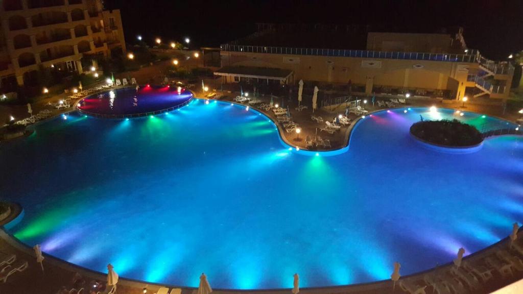 uma grande piscina à noite com luzes azuis em PSB Deluxe Apartments Aheloy em Aheloy