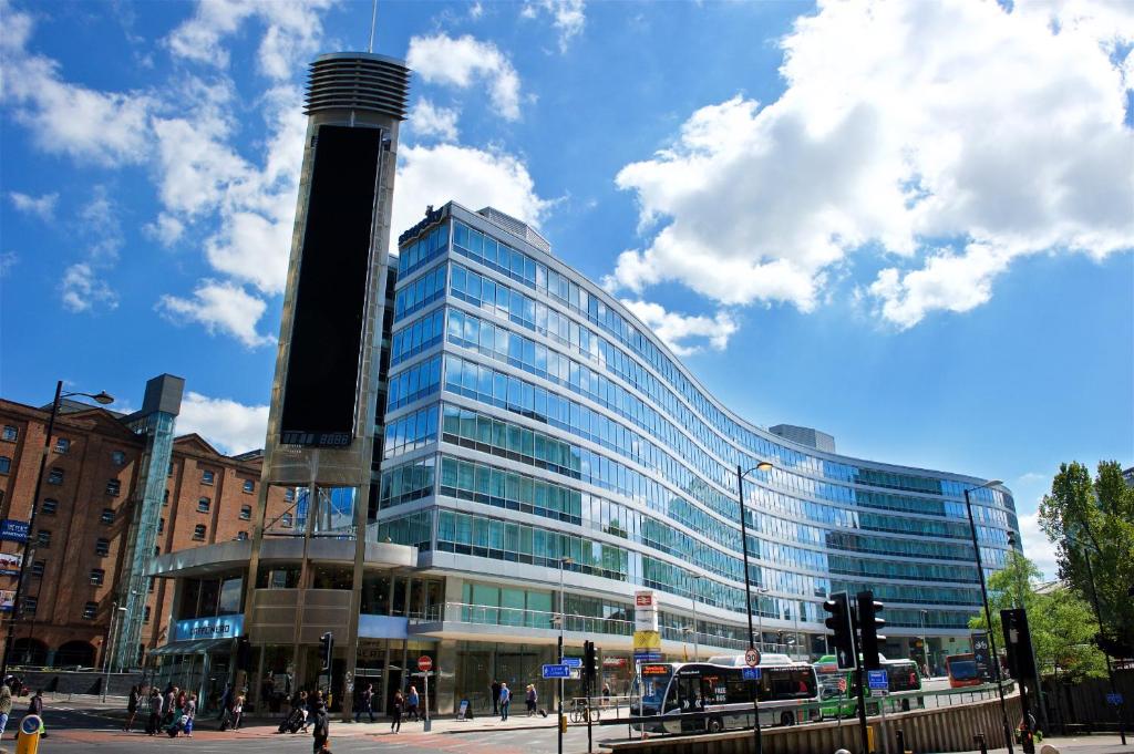 a tall glass building with people walking in front of it at Staycity Aparthotels Manchester Piccadilly in Manchester