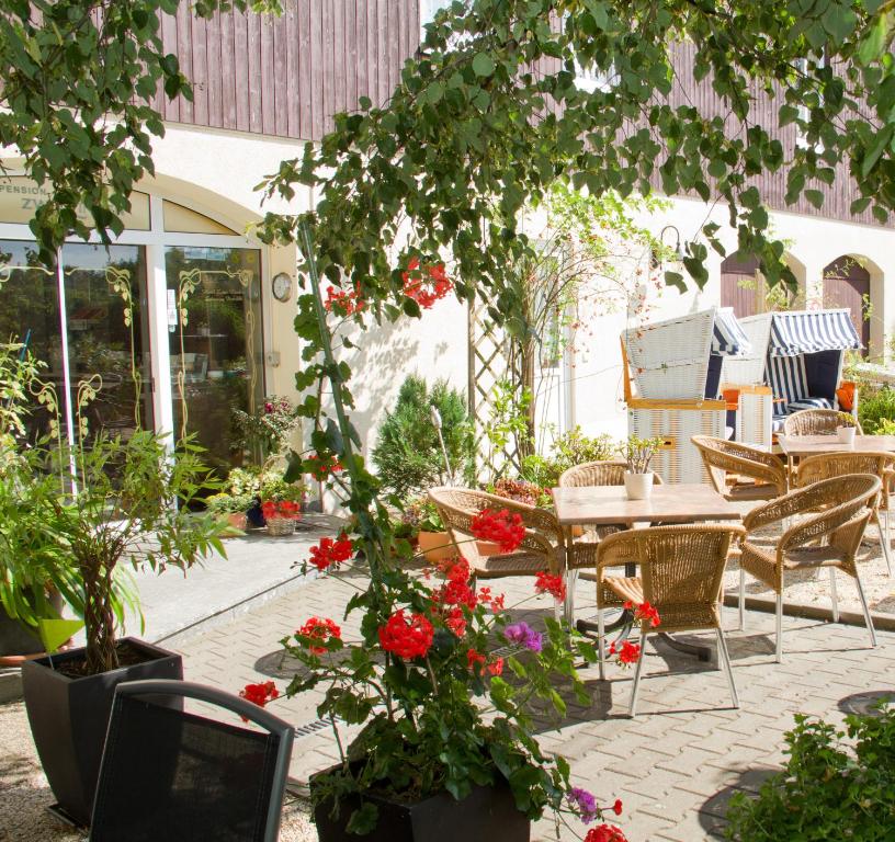 um pátio com uma mesa, cadeiras e flores em Hotel Zwei Linden em Ottendorf-Okrilla