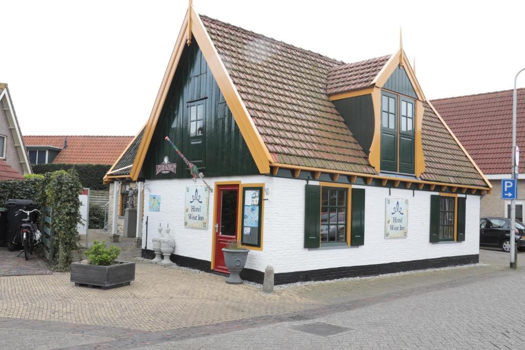 a small white building with a brown roof at Hotel West Inn in Hippolytushoef