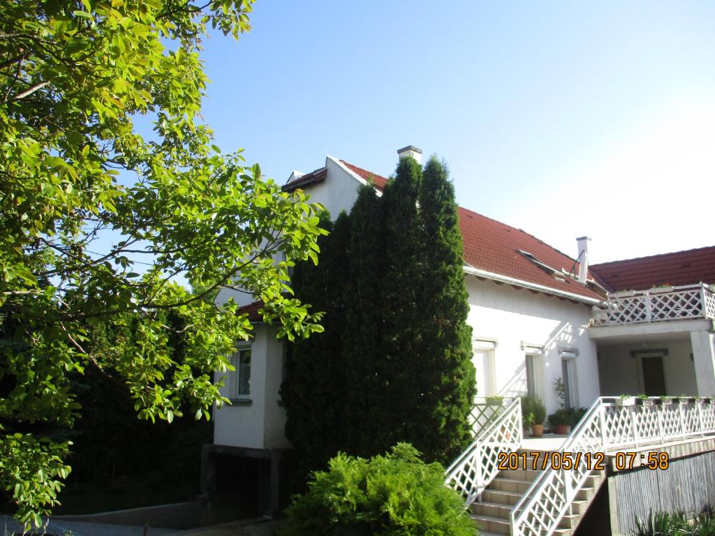 a white house with a white staircase and a hedge at Boglárka Apartmanház in Balatonfüred