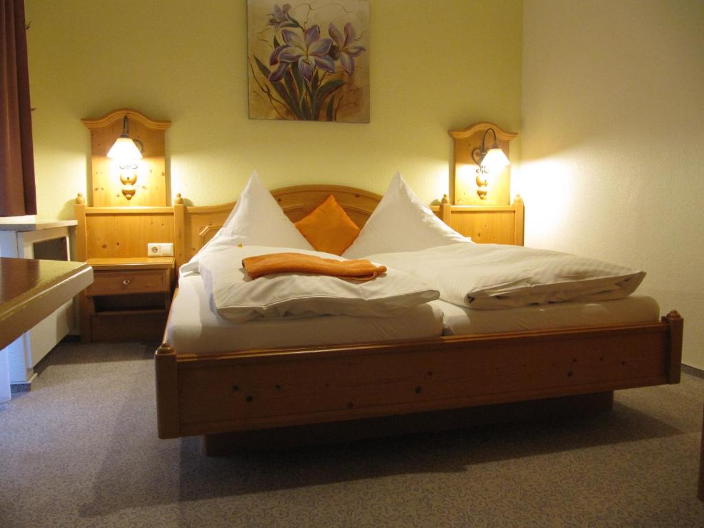 a bedroom with a bed with white sheets and two lights at Hotel Gasthof am Selteltor in Wiesensteig